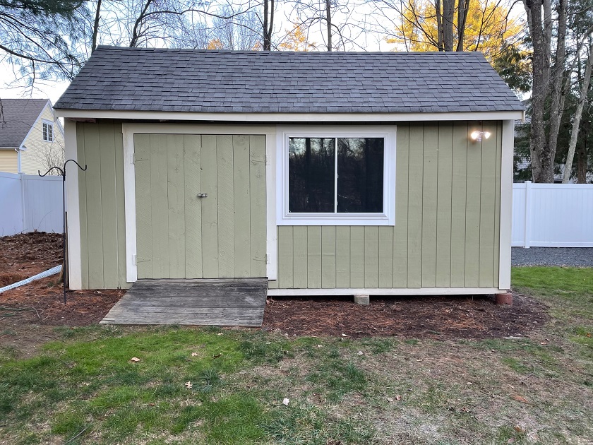 Slide 5: This picture shows the outside of the building that the newly constructed window has been added to, just right of the door. This new window will add ample natural light to the inside of the shed. 